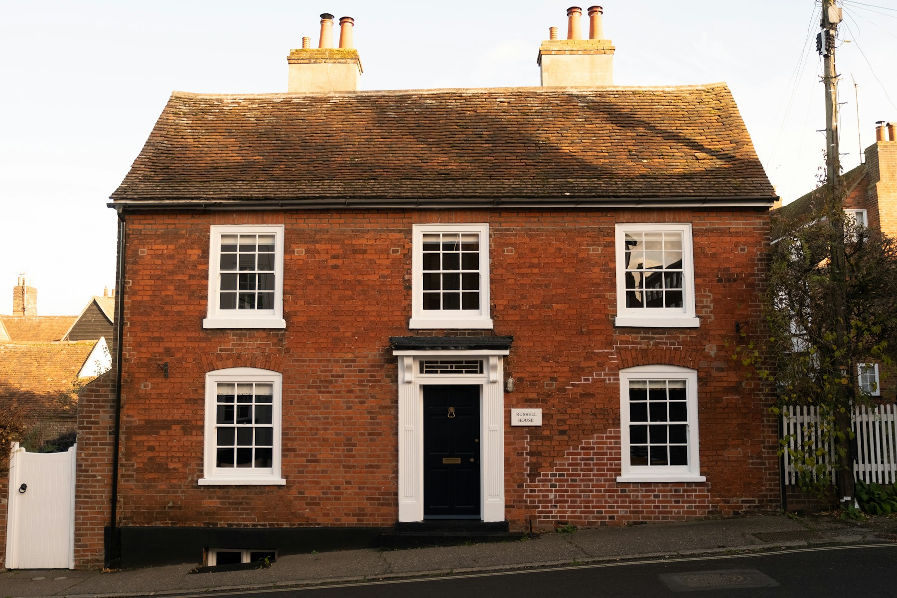 A red-brick UK semi-detached house with white sash windows and a black front door, the kind of property typically suitable for cavity wall insulation